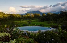 Swimming pool with clean water located near exotic plants in green valley near mountain peak in cloudy evening in Costa Rica — Stock Photo