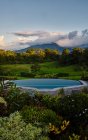 Swimming pool with clean water located near exotic plants in green valley near mountain peak in cloudy evening in Costa Rica — Stock Photo