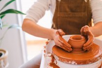 High angle of crop person in casual clothes making handmade pottery using special equipment while working in light contemporary studio — Stock Photo
