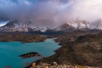 From above breathtaking landscape of calm river with turquoise water in highland against snowy mountains peaks among dramatic clouds — Stock Photo