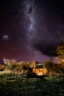 Чудовий краєвид з одиночним табором на галявині між деревами під фіолетовим небом з Чумацьким Шляхом серед більшості зірок. — стокове фото