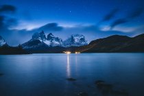 Paesaggio mozzafiato di lago tranquillo sotto cielo stellato chiaro contro rocce innevate durante la notte tranquilla — Foto stock