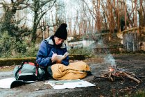 Junge Backpackerin macht sich Notizen am Lagerfeuer — Stockfoto