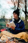 Young female backpacker making notes at campfire — Stock Photo