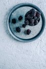 From above cup with ripe blackberries placed on metal tray on plaster surface — Stock Photo