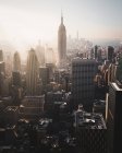 De arriba de los grandes rascacielos modernos con las paredes de cristal contra el cielo azul y el sol en Nueva York - foto de stock