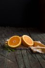 Галявини свіжих апельсинів на дерев'яному темному сільському столі на темному фоні — стокове фото