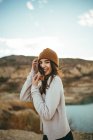 Vista lateral da alegre jovem encantadora turista olhando para a câmera enquanto desfruta de viagem de fim de semana ao lago no outono — Fotografia de Stock
