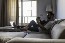 Stylish guitarist on couch in living room — Stock Photo