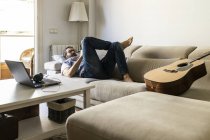 Чоловік пише нотатки на дивані в затишній вітальні — стокове фото