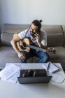 Молодий чоловічий музикант телефонує на смартфон у вітальні — стокове фото