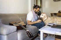 Casual gars mettre des écouteurs sur chien dans le salon — Photo de stock