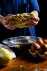 Анонимная женщина смешивает свежее тесто за столом с лимоном и салфеткой во время приготовления выпечки дома — стоковое фото