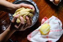 Зверху анонімні жінки замішують свіже тісто над столом з лимоном і серветкою під час приготування тіста в домашніх умовах — стокове фото