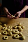 Anonymous woman making rings from soft dough while preparing doughnuts over table in kitchen — Stock Photo