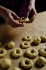 Donna anonima che fa anelli di pasta morbida mentre prepara ciambelle sul tavolo in cucina — Foto stock