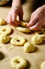 D'en haut femme anonyme faire des anneaux de pâte molle tout en préparant des beignets sur la table dans la cuisine — Photo de stock
