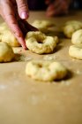 Femme anonyme faisant des anneaux à partir de pâte molle tout en préparant des beignets sur la table dans la cuisine — Photo de stock