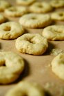 Par dessus les anneaux de pâte molle tout en préparant des beignets sur la table dans la cuisine — Photo de stock