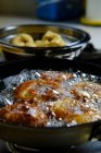 De arriba manojo de deliciosas rosquillas fritas en aceite burbujeante caliente en la estufa en la cocina - foto de stock