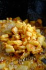 Vue de dessus des tranches de pommes de terre crues jaunes dans une grande casserole en métal avec de l'huile bouillante et des bulles dans la cuisine — Photo de stock