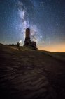 Back view of faceless traveler sightseeing remains of ancient castle under Milky Way at starry night with lantern light — Stock Photo