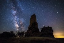 Rückansicht der gesichtslosen Reisenden Besichtigung Überreste einer alten Burg unter der Milchstraße in sternenklarer Nacht mit Laternenlicht — Stockfoto