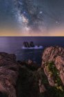 Big rough cliffs on blue calm ocean during bright evening under colorful starry sky with milky way — Stock Photo