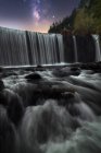 Bela cachoeira rochosa poderosa e fluxo de água com céu estrelado noite colorida no fundo — Fotografia de Stock