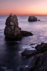 D'en haut décor pittoresque de rochers rugueux au milieu d'une mer bleue calme sous un ciel nocturne coloré avec des rayons de soleil brisant les nuages au crépuscule Costa Brava, Espagne — Photo de stock
