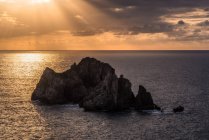 From above picturesque scenery of rough rocks among calm blue sea under colorful evening sky with sun beams breaking through clouds during twilight Costa Brava, Spain — Stock Photo