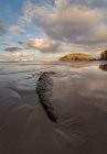 Grandes formations rocheuses sur une plage sablonneuse vide de l'océan avec ciel nuageux et clair en soirée sur fond — Photo de stock