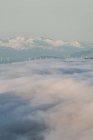 Dall'alto di cime nere di montagne potenti tra nubi spesse bianche morbide — Foto stock