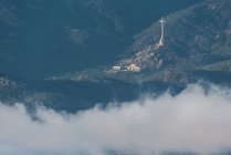 Desde arriba de la ciudad vieja en la pendiente de la colina entre el bosque verde cubierto de niebla gruesa bajo el cielo colorido de la mañana - foto de stock