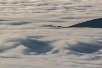 D'en haut des sommets noirs des montagnes puissantes parmi les nuages épais blancs doux — Photo de stock