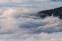 Von oben von schwarzen Gipfeln mächtiger Berge inmitten weicher weißer dicker Wolken — Stockfoto
