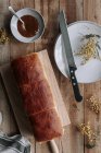 Сверху вид на прямоугольную буханку свежего бриошского хлеба на деревянном столе с вареньем и ножом — стоковое фото