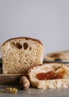 Сверху кусок вкусного булочного хлеба на столе с буханкой на деревянной доске на кухне — стоковое фото