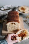 De cima da mão de colheita que toma o pedaço de pão Brioche saboroso com lam na mesa com pão na tábua de madeira na cozinha — Fotografia de Stock