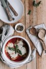 Von oben Keramikschale mit gebratenen Hühnerstücken mit Parmesan und Basilikum in Tomatensauce auf Holztisch in der Nähe von Servietten und Geschirr platziert — Stockfoto
