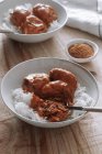 Dall'alto ciotole di riso e deliziose polpette di lenticchie con salsa al curry poste vicino a spezie e tovagliolo sul tavolo di legno a casa — Foto stock