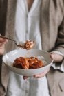 Femme méconnaissable prenant savoureux curry lentilles boulettes de viande avec du riz à la fourchette tout en mangeant pendant le déjeuner à la maison — Photo de stock