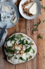 Top view of tasty pear salad with arugula placed on timber near cheese and walnuts in kitchen — Stock Photo