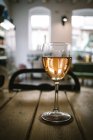 Bicchiere di vino posto su tavola di legno contro la luce del giorno dalle finestre del ristorante rustico — Foto stock