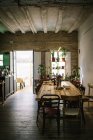 Grande tavolo e sedie in legno in stile rustico retrò bar con soffitto squallido e piante verdi in vaso sulla finestra — Foto stock
