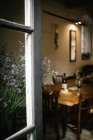 Fragment des Interieurs eines rustikalen Restaurants mit Holztisch, serviert mit Wein und Käse, vom offenen Fenster mit Blumen aus gesehen — Stockfoto