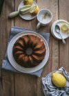 Vista superior de cima saboroso bolo vegan fresco com limão e coco na mesa de madeira com ingredientes — Fotografia de Stock