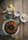 Вид зверху на смачний свіжий веганський торт з лимоном і кокосом на дерев'яному столі з інгредієнтами — стокове фото