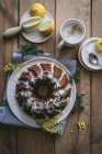 Вид сверху вкусный свежий веганский торт с лимоном и кокосом, покрытый глазурью на деревянном столе с ингредиентами — стоковое фото