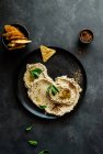 Top view of stylish black plate with delicious fresh eggplant and cauliflower dip stylish decorated with colorful spices and leaves of mint — Stock Photo